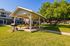 Charming outdoor community space featuring a covered pavilion with picnic tables, perfect for gatherings under the bright blue sky, surrounded by lush greenery.