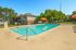 Inviting apartment community pool area with sun loungers, vibrant umbrellas, and lush green surroundings, perfect for relaxation.