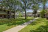 Charming apartment complex with lush green lawns, mature trees, and a tranquil outdoor setting.