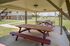 Inviting outdoor pavilion with wooden picnic tables overlooking a serene apartment complex courtyard.