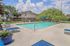 Inviting outdoor pool area with comfortable loungers, surrounded by lush greenery and a charming apartment building in the background.