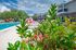 Vibrant poolside oasis with lush greenery and blossoming flowers, offering a serene escape in a modern apartment community.