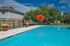Inviting community pool with vibrant orange umbrella and lush greenery, perfect for relaxation and leisure.