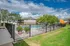Inviting apartment community pool area with vibrant orange umbrellas, surrounded by lush greenery and sun loungers under a bright blue sky.