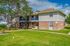 Charming apartment complex with brick and siding exterior surrounded by lush green lawns and mature trees, offering a welcoming and serene living environment.
