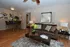 Elegant living room showcasing a cozy brown sofa with patterned cushions, modern decor, and a sleek wooden coffee table, set against warm neutral walls with artistic wall hangings.
