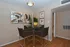 Chic dining nook with contemporary art, elegant round glass table, and modern chairs on warm wooden floors.