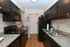 Modern kitchen with sleek black appliances, granite countertops, and stylish dark cabinets, offering a contemporary cooking space.