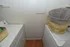 Compact laundry room with modern washer, dryer, and stylish laundry basket on a wood-look floor.