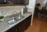 Elegant kitchen with stone backsplash, double sink, and sleek dark cabinetry complemented by chic decorative accents.