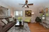 Inviting living room with elegant decor, featuring a plush brown sofa, vibrant yellow armchair, modern ceiling fan, and chic accents, perfect for relaxation.