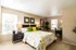 Cozy bedroom with elegant floral bedding, modern decor, and natural light streaming through large windows.