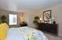 Inviting bedroom with vibrant floral bedding, elegant decor, and natural light streaming through a window, complemented by lush greenery.
