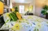 Inviting bedroom with vibrant floral bedding, abundant natural light, and cozy workspace corner.