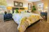 Cozy bedroom with vibrant floral bedding, elegant decor, and natural light through large windows.