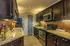 Elegant kitchen featuring granite countertops, rich dark wood cabinets, modern stainless steel appliances, and warm under-cabinet lighting.