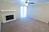 Inviting living room with plush carpet, a modern ceiling fan, and elegant fireplace, featuring ample natural light from vertical blinds.