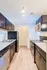 Modern kitchen with sleek dark wood cabinets, stainless steel appliances, and elegant granite countertops, highlighted by contemporary track lighting and warm wood flooring.