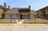 Inviting leasing office with charming stone facade and vibrant flower beds at a modern apartment complex.