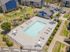 Inviting aerial view of a modern apartment complex, showcasing a pristine swimming pool with surrounding lounge chairs, cozy gazebos, and lush green landscaping for relaxation and leisure.