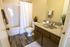 Modern bathroom featuring elegant wood flooring, sleek countertop, and a fresh white shower curtain for a tranquil atmosphere.