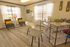 Inviting modern office space with natural light, featuring elegant wood flooring, cozy gray chairs with vibrant yellow pillows, and a sleek white desk adorned with greenery.