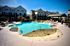 Luxurious apartment complex with a sparkling resort-style pool, surrounded by elegant lounge chairs and shaded seating areas, perfect for relaxation.