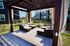 Inviting outdoor seating area under a stylish pergola, featuring cozy cushions and elegant curtains, perfect for relaxation and social gatherings.