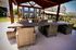 Charming outdoor patio with elegant wicker furniture and a view of modern apartment buildings, perfect for relaxation and social gatherings.