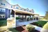 Charming outdoor communal area with covered seating, barbecue grills, and lush landscaping, perfect for gatherings and relaxation.