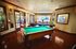 Luxurious recreation room with a sleek billiards table and vibrant natural light, perfect for entertainment and relaxation.
