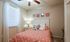 Cozy bedroom with modern decor, featuring a vibrant orange-patterned bedspread, elegant side table, and stylish wall art.