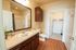 Elegant bathroom featuring rich wooden cabinetry, sleek countertops, and a spacious walk-in closet in a modern apartment.