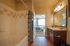 Inviting bathroom with elegant tile work and modern fixtures leading to a cozy bedroom with natural light accentuating the plush carpet and stylish decor.