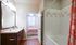 Inviting bathroom with modern fixtures, warm wood cabinetry, and a cozy view into a sunlit bedroom.