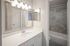 Modern bathroom with sleek vanity, illuminated mirror, and elegant stone-tiled shower for a luxurious experience.