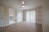 Bright and airy living room with elegant hardwood flooring, modern ceiling fan, and built-in shelving, featuring large sliding doors for natural light.