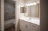 Bright and modern bathroom with elegant vanity, large mirror, and sleek tiled bathtub.