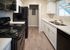 Modern kitchen with sleek black appliances, elegant white cabinets, and stylish hardwood floors.
