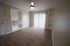 Contemporary living area with elegant wood flooring, built-in shelves, and sleek ceiling fan, bathed in natural light.