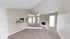 Bright and airy living space featuring vaulted ceilings, a cozy fireplace, plush carpeting, and a modern kitchen pass-through window.
