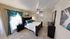 Chic bedroom with elegant teal accents, ceiling fan, and cozy beige carpeting for a serene atmosphere.