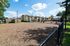 Charming apartment complex with inviting playground, surrounded by lush greenery and blue skies.