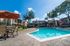 Inviting apartment complex featuring a sparkling blue swimming pool surrounded by lush greenery and comfortable outdoor seating under vibrant umbrellas.