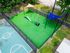 Aerial view of a vibrant outdoor dog park with agility equipment and colorful sunshades, next to a well-maintained basketball court.