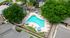 Inviting aerial view of a sparkling pool surrounded by lush greenery and relaxing lounge chairs in a serene apartment complex.