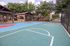 Inviting outdoor basketball court surrounded by lush green trees and cozy picnic area, ideal for active and social living.