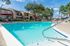 Inviting outdoor pool area with crystal-clear water, surrounded by lush greenery and modern apartment buildings.