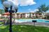 Charming apartment complex accompanied by a sparkling outdoor pool, inviting lounge chairs, and vibrant umbrellas under a clear blue sky.