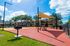 Charming outdoor communal space with shaded picnic areas, vibrant red pavement, and spacious walkways, perfect for gatherings in a welcoming apartment complex.